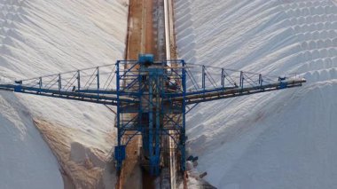 İspanya 'nın Santa Pola kenti yakınlarındaki büyük beyaz tuz yığınlarının hava manzarası, yumuşak öğleden sonra ışığı altında höyüklerle mavi Akdeniz' i ayıran bir taşıyıcı sistem. Yüksek kalite 4k