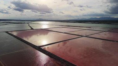 İspanya 'nın Santa Pola kenti yakınlarındaki renkli tuz göletlerinin, bulutları ve Akdeniz kıyısındaki güneş ışığını yansıtan pembe ve yeşil sularla hava aracı görüntüsü. Yüksek kalite 4k görüntü