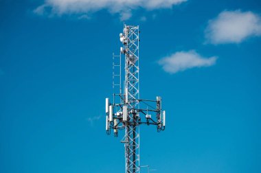 Telekom ekipmanları ve ağ altyapısını gösteren açık mavi gökyüzüne karşı modern anten ve kablolarla hücresel iletişim kulesi. Yüksek kalite fotoğraf