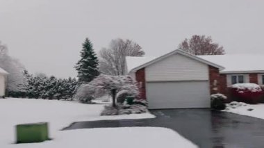 Kar kaplı banliyö evleri, kırmızı çalılar, tuğla cephe ve kış ağaçları sessiz bir Amerikan mahallesinde hareket halindeki bir araçtan ele geçirildi. Yüksek kalite 4k görüntü