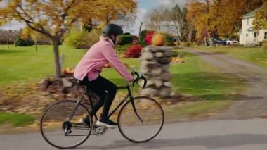 Orta yaşlı bir kadın sessiz bir Amerikan mahallesinde bisiklet sürüyor, açık hava egzersizinden ve aktif ve sağlıklı bir yaşam tarzından hoşlanıyor. Yüksek kalite 4k görüntü