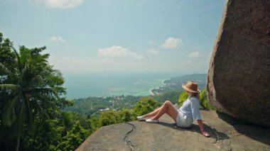 Kadın, Koh Samui 'de deniz ve kıyı şeridine bakan uçurum manzarasında dinleniyor. Yüksek kalite 4k görüntü