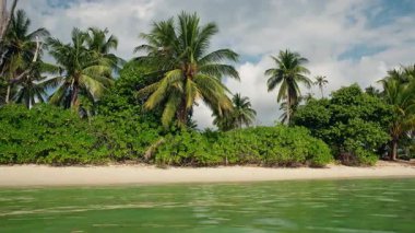 Hindistan cevizi palmiyeleri ve kumlu kıyı şeridi boyunca yemyeşil bitki örtüsü olan tropik plaj Koh Samui 'deki Lipa Noi' de bulutlu gökyüzü ve sakin sığ deniz altında. Yüksek kalite 4k görüntü