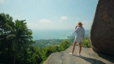 Koh Samui 'de tropikal kıyı şeridine ve denize bakan uçurum manzaralı bir kadın. Yüksek kalite 4k görüntü