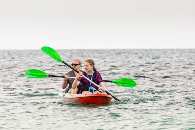 Tayland 'da tropikal denizde kayak yapan iki genç kız açık deniz sporu ve yaz seyahati macerasının keyfini çıkarıyorlar. Yüksek kalite fotoğraf