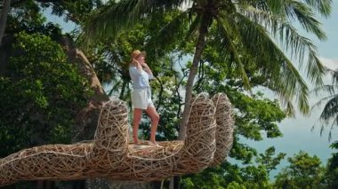 Orta yaşlı bir kadın Koh Samui 'deki tropik palmiye ağaçları arasında el yordamıyla duruyormuş. Yüksek kalite 4k görüntü