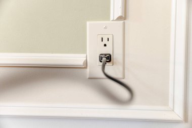 Beyaz pervazlı ve yumuşak doğal ışıkla dekoratif iç duvardaki Amerikan duvar prizine bağlı güç kablosu. Yüksek kalite fotoğraf