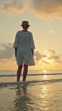 Gün batımında ve Lipa Noi plajında gün doğumunda yalın ayak ayakta duran genç kadın, Koh Samui, altın gökyüzü ile huzurlu bir tropikal seyahat anı. Yüksek kalite 4k görüntü