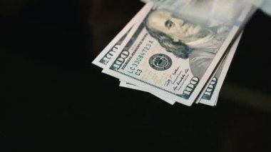 Ellerini masanın üzerine yüz dolarlık banknot yaymak