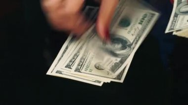 Ellerini masanın üzerine yüz dolarlık banknot yaymak