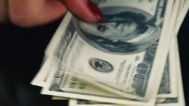 Ellerini masanın üzerine yüz dolarlık banknot yaymak