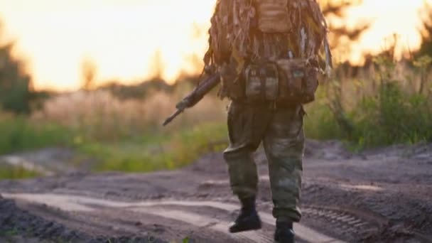 Een man in camouflage pak met armen in de verte. Airsoft spel — Stockvideo