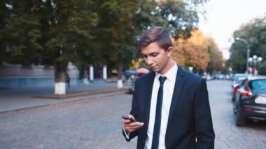 Genç işadamı, sokakta yürürken cep telefonundan konuşuyor