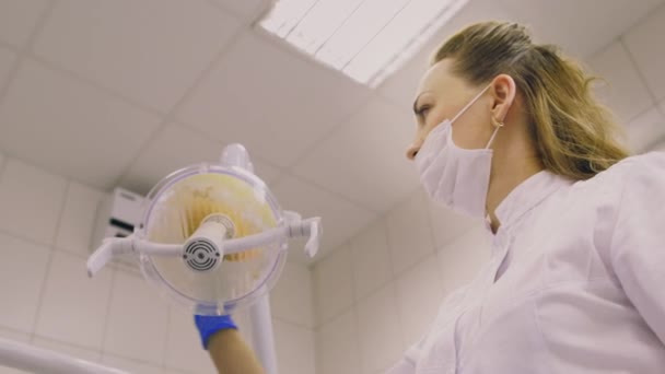 El dentista enciende una lámpara y la pone. Clínica dentista — Vídeos de Stock