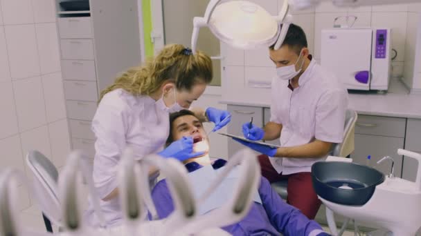 Dentista e seu assistente examinam um paciente — Vídeo de Stock