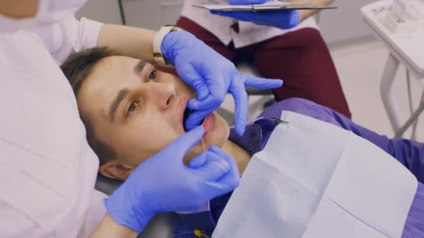 El dentista y su asistente examinan a un paciente — Vídeo de stock