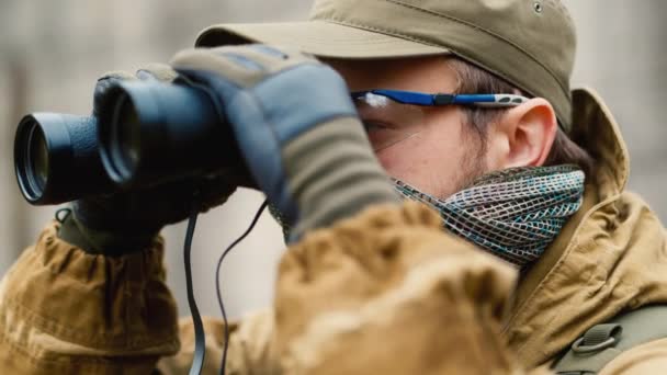 Hombre en camuflaje mirando a través de binoculares — Vídeos de Stock