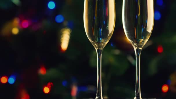 Due bicchieri di champagne sullo sfondo dell'albero di Natale. La celebrazione del Natale e del Capodanno — Video Stock