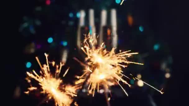 Bengalas ardientes en el fondo del árbol de Navidad y copas de champán. La celebración de la Navidad y Año Nuevo — Vídeo de stock