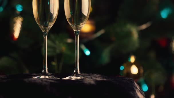 Dos copas de champán en el fondo del árbol de Navidad. La celebración de la Navidad y Año Nuevo — Vídeos de Stock
