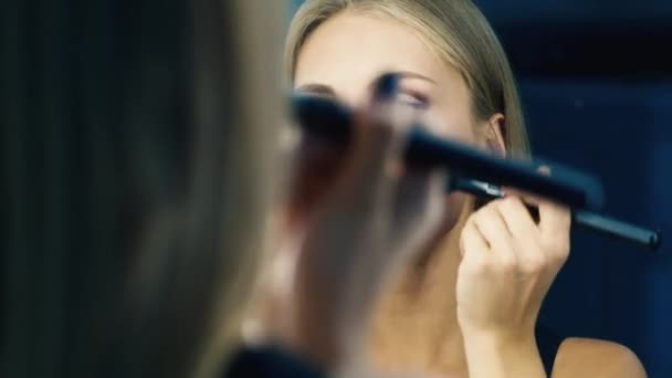 Ragazza attraente facendo il trucco in uno specchio — Video Stock