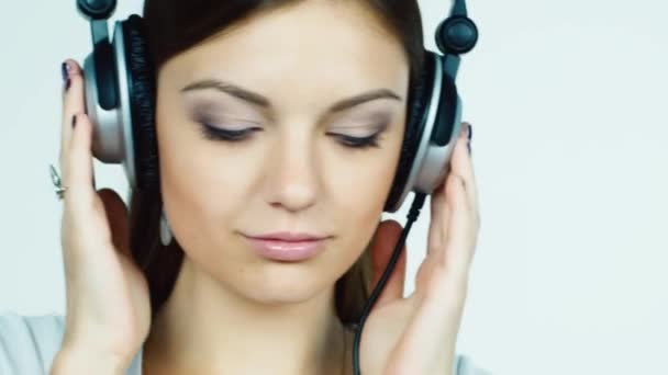 Привлекательная темноволосая девушка надевает наушники и слушает музыку — стоковое видео