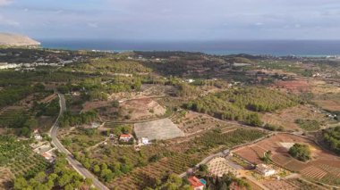 Kosta Blanca kıyısı boyunca ağaçların altında bahçeleri, dolambaçlı yolları ve Akdeniz ufkuyla kaplı havadan kırsal alanlar. Yüksek kalite 4k görüntü