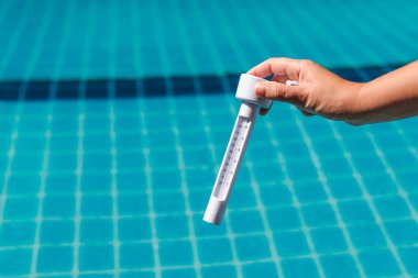 Yüzme havuzu bakımında su ısısını ölçen el kamerası termometresi ve arka planda açık mavi fayanslar. Yüksek kalite fotoğraf