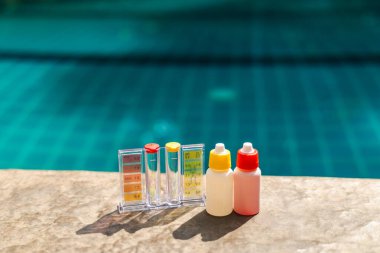 PH ve klor ölçülü havuz suyu test kiti ve havuz kenarında reaksiyonlu şişeler, yüzme havuzu bakımı ve su kalite kontrol kavramı. Yüksek kalite fotoğraf