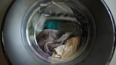 Modern ev aletlerinde aktif yıkama döngüsü sırasında çamaşır makinesinin içinde dönen çamaşırhane varilleri.