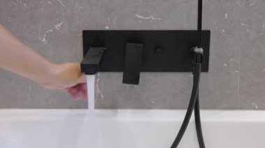 Küvet duvarında modern banyo musluğu mikserini döndürmek, çağdaş banyo içlerindeki su akışını ayarlamak..