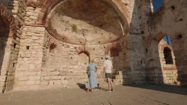 Bulgaristan 'ın Nessebar kentindeki antik kilise kalıntılarını taş kemerlerle gezen turistler.
