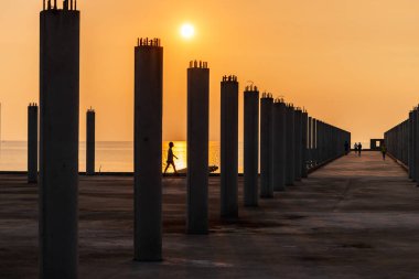 Tropikal deniz kıyısında gün batımında iskelenin beton sütunları..