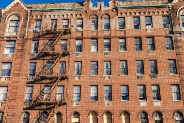 Brick apartment building facade with fire escape stairs in New York city