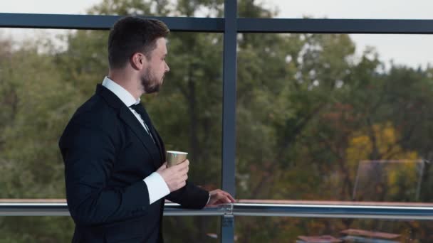 Молодий бізнесмен п'є каву у вікні офісу — стокове відео