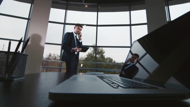 Mladý podnikatel v obleku mluví po telefonu v moderní kancelářské — Stock video