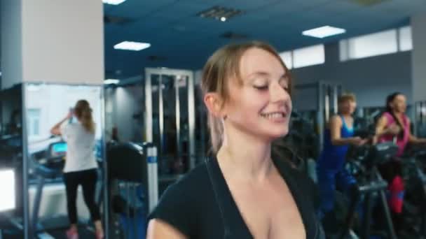 Atractiva mujer entrenando en una cinta de correr, sonriendo — Vídeo de stock
