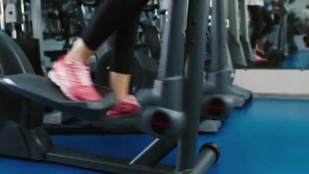 Training in the gym on the elliptical trainer feet — Stock Video