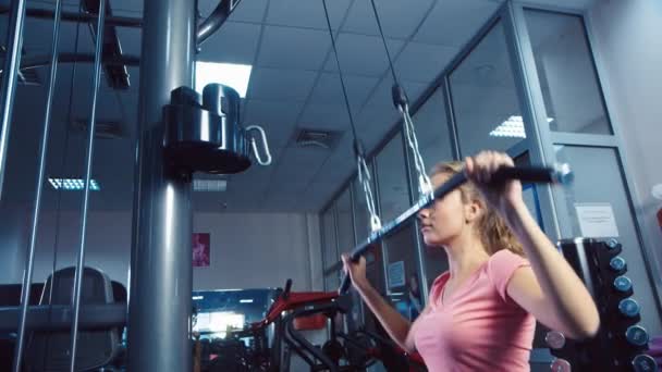 Una chica atractiva en el simulador de entrenamiento en el gimnasio — Vídeos de Stock