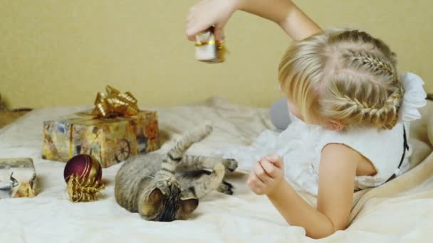 Blondes Mädchen spielt mit einem Kätzchen in der Nähe der Weihnachtsgeschenke — Stockvideo