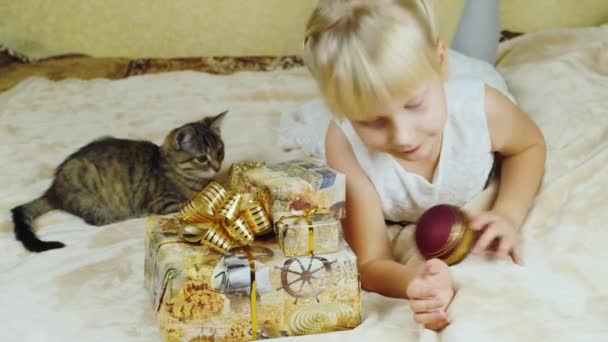 Menina loira brincando com um gatinho perto dos presentes de Natal — Vídeo de Stock