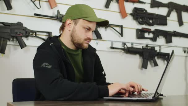 Een wapenhandelaar op het werk, werken met een laptop — Stockvideo