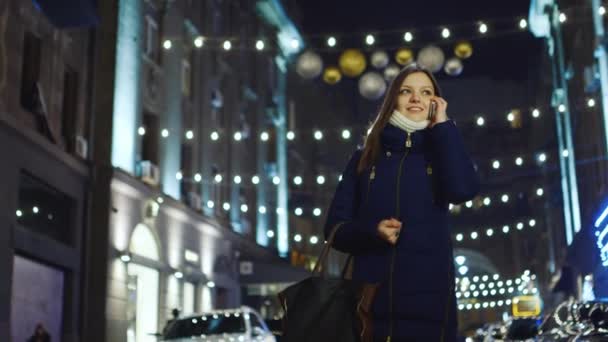 Mujer hablando en una celda, caminando por la ciudad nocturna — Vídeos de Stock