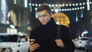 Genç bir adam sokakta yürüyor ve sms okur
