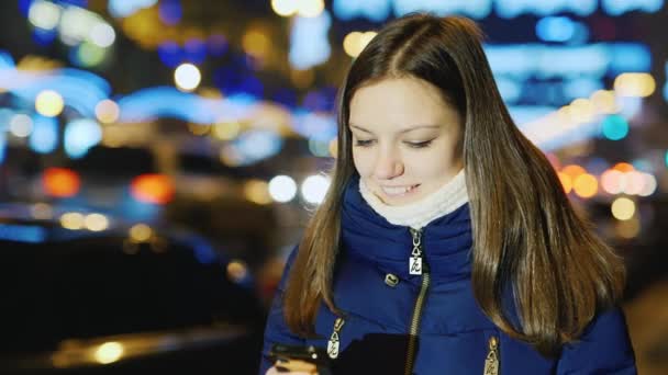 Jonge vrouw in de stad van de nacht met de telefoons scherm lezen — Stockvideo