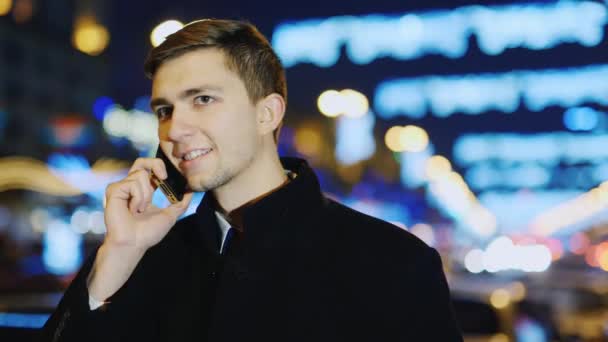 A young man talking on the phone, smiling, then looks into the camera — Stock Video