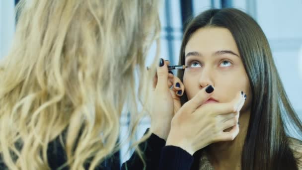Uma jovem garota aplicar maquiagem ao redor dos olhos — Vídeo de Stock