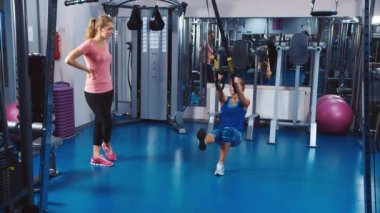 Eğitmen ziyaretçi egzersizler fitness ekipmanları üzerinde gösterir.