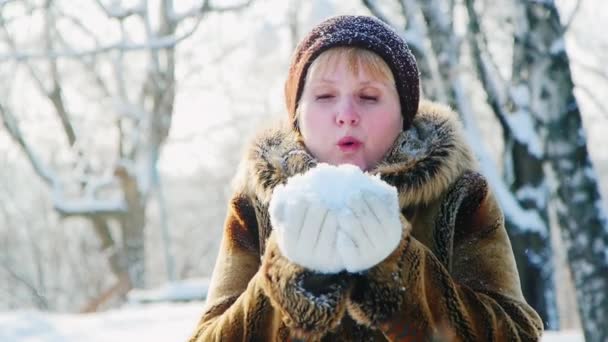 Diversión invernal - mujer soplando en la nieve en sus palmas — Vídeo de stock