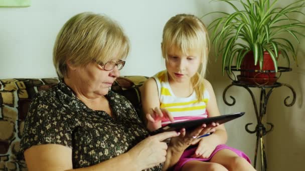 Barnbarn och mormor spelar på tabletten — Stockvideo